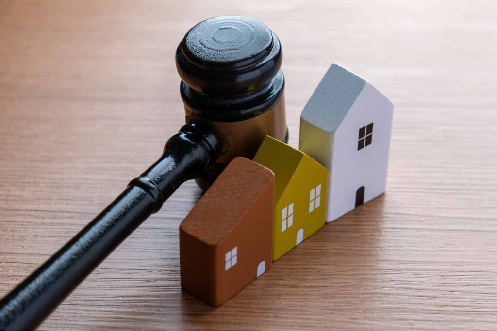 Haus geerbt: Richterhammer und kleines Haus als Symbol für Erbschaft und Immobilienverkauf