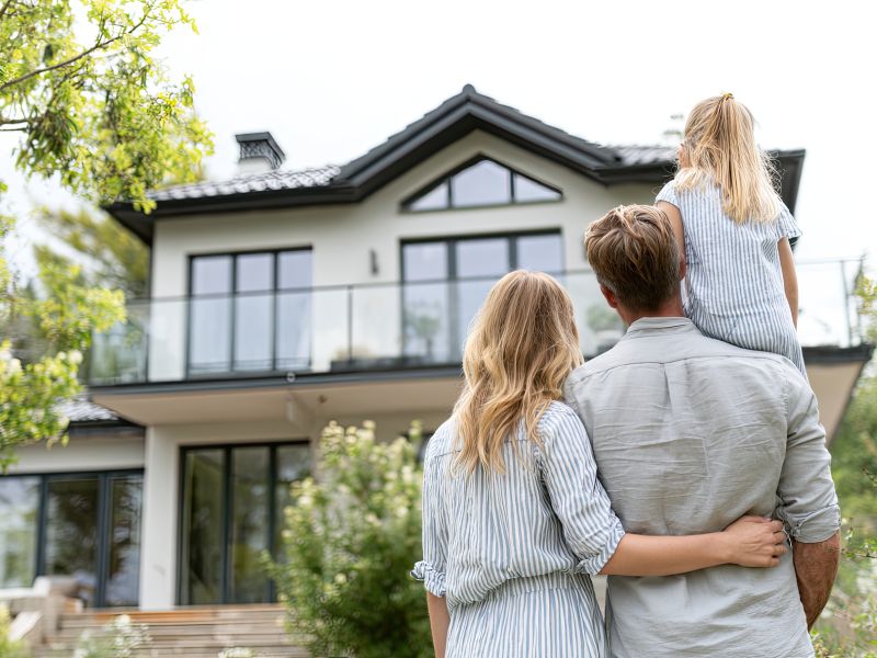 Grunderwerbsteuer-Entlastung: Familie vor einem Wohnhaus